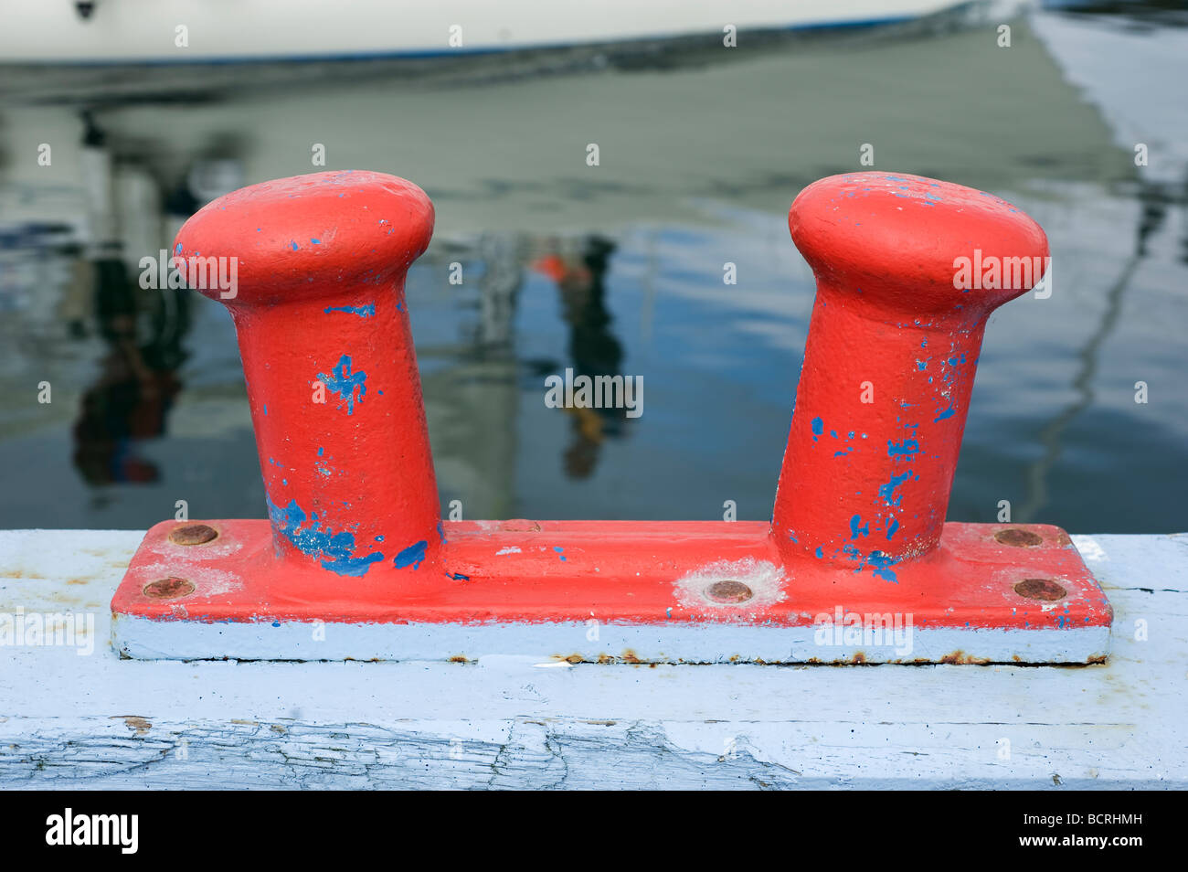 bollard in harbour with reflexions of sailingboat in background, Denmark Stock Photo