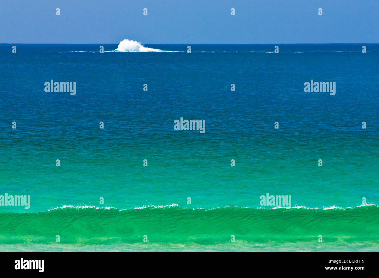 Surf breaks on reef across green and blue sea Stock Photo