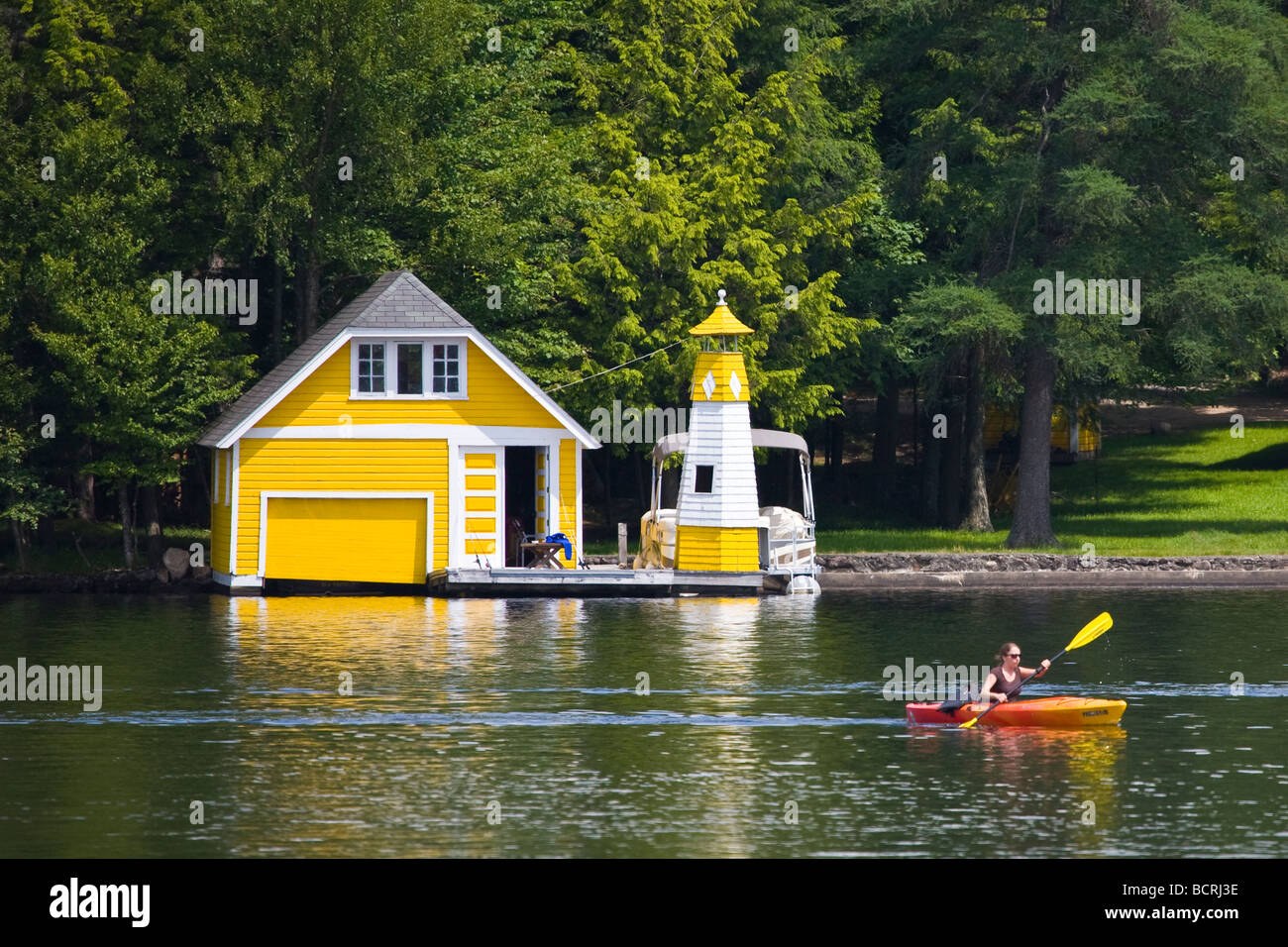 Yellow boathouse and lighthouse in Old Forge Pond in the Adirondack Mountains of New York Stock Photo