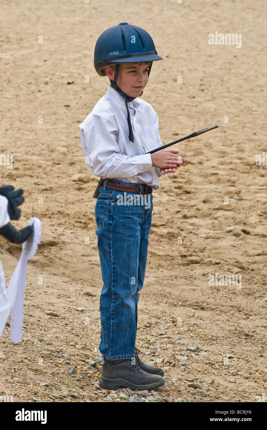 Young boy claps & awaits awarding of prize ribbons at horseback riding lesson Stock Photo Alamy