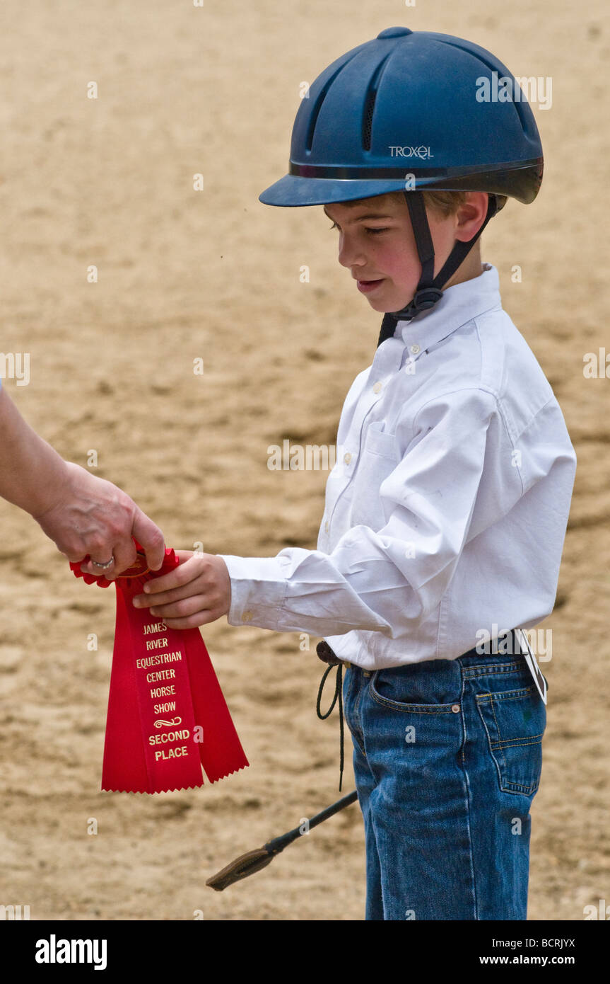 Young boy accepts prize ribbon at horseback riding lesson Stock Photo