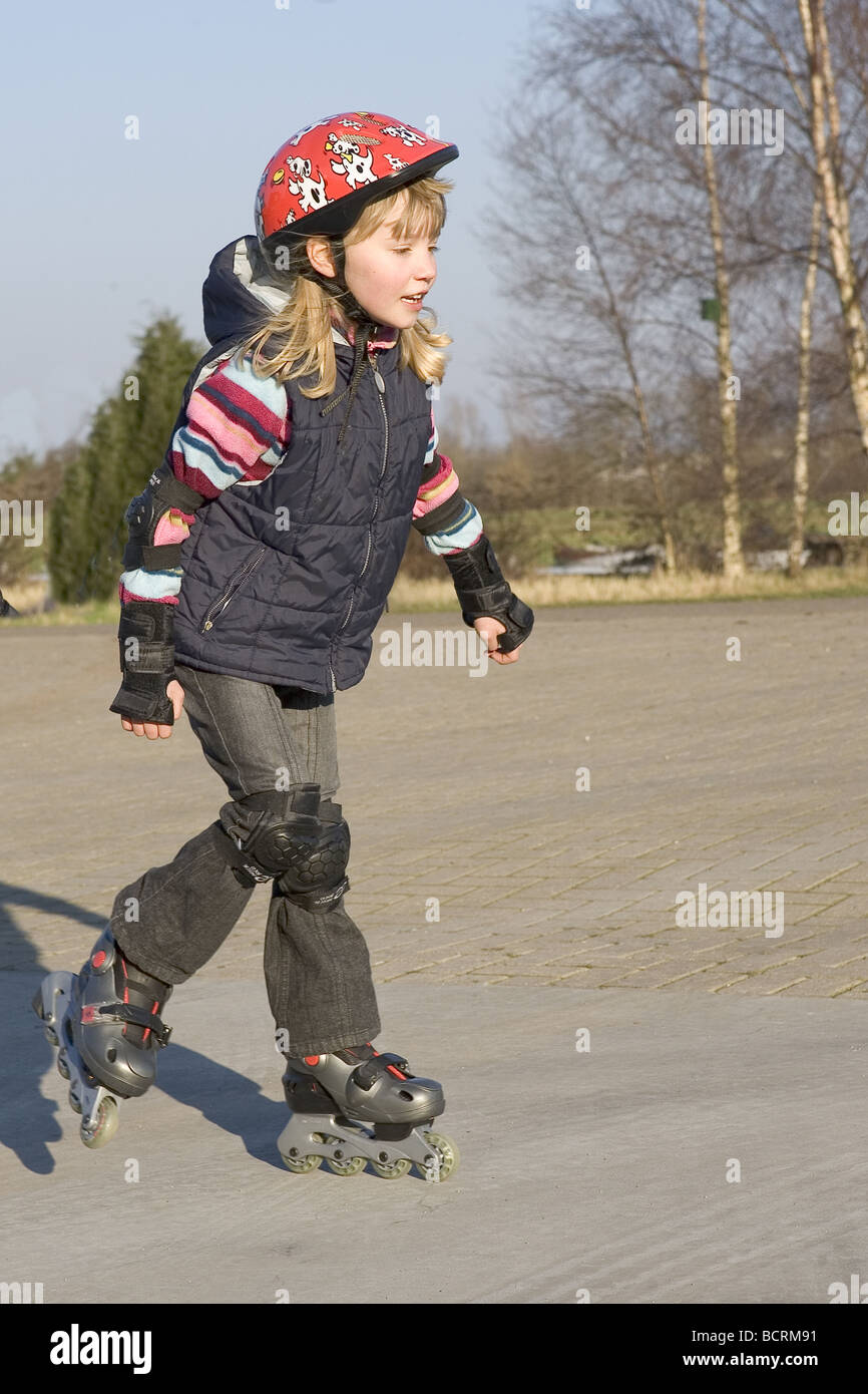 Child with safety helmet roller skating outdoors girl, physical