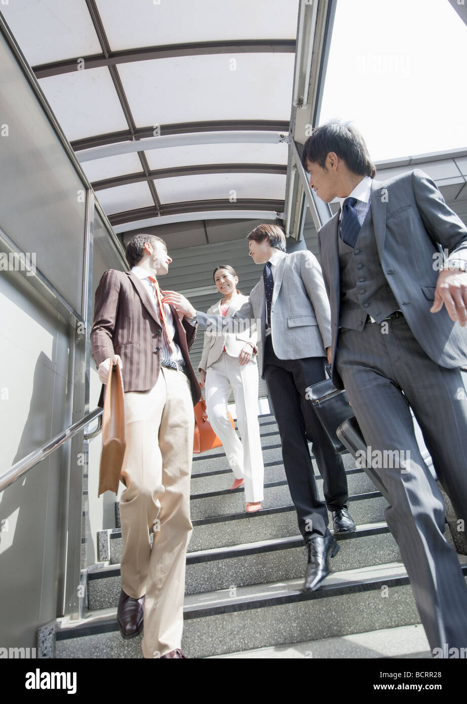 Businessmen and businesswoman walking down stairs Stock Photo - Alamy
