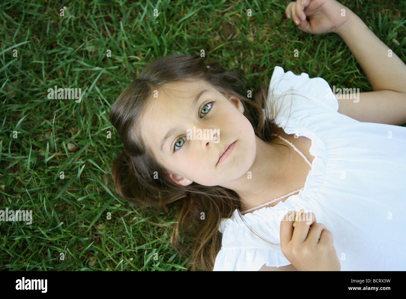 Portrait of young girl lying on grass in park Stock Photo - Alamy
