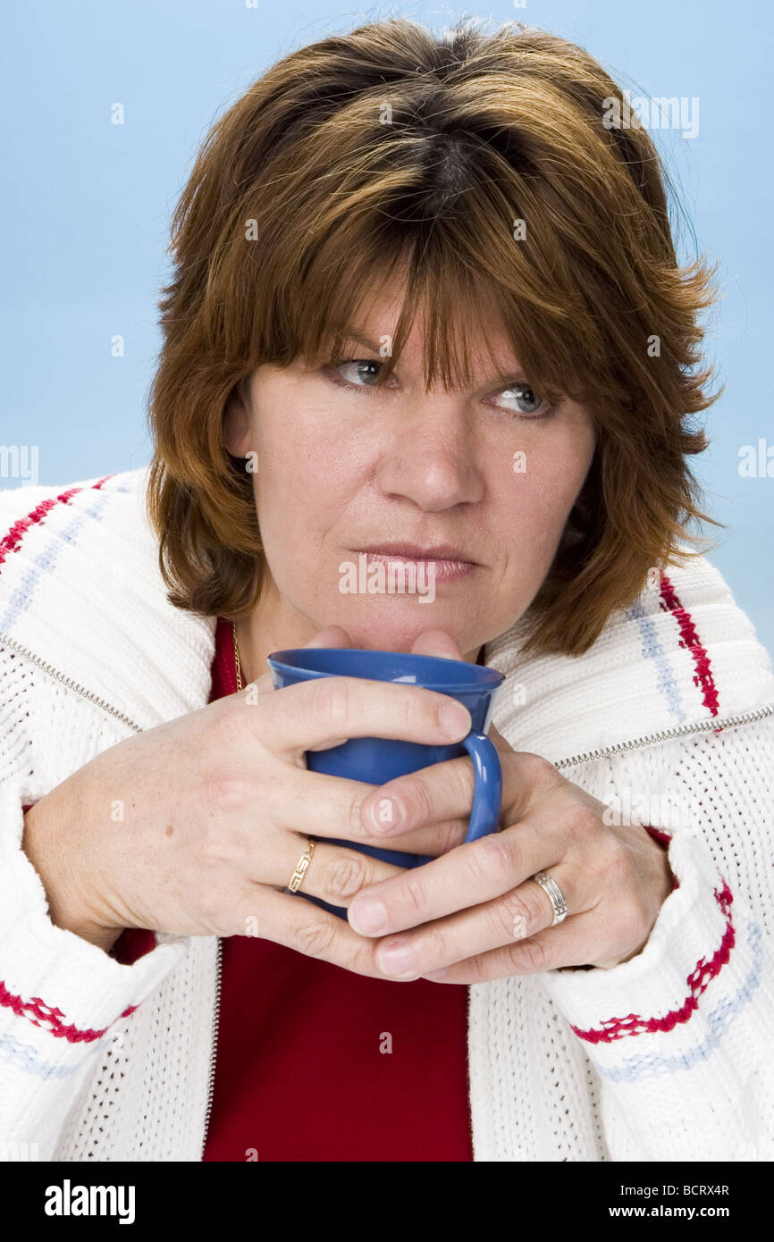 Grumpy adult white woman drinking coffee and contemplating Stock Photo