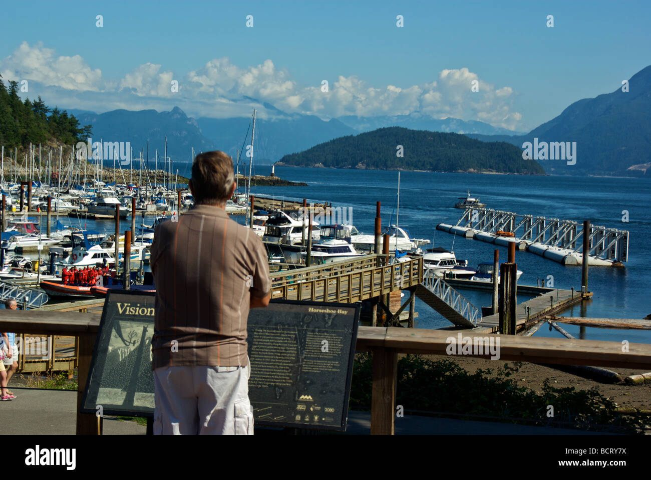 Tourist looking at spectacular mountain water views north to Howe Sound from Horseshoe Bay marina Stock Photo