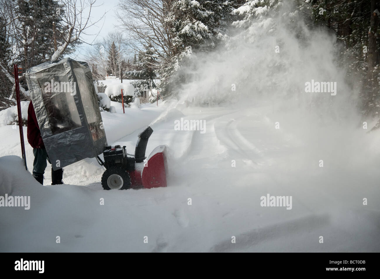 senior behind a plastic shelter with snow blower after storm in Quebec