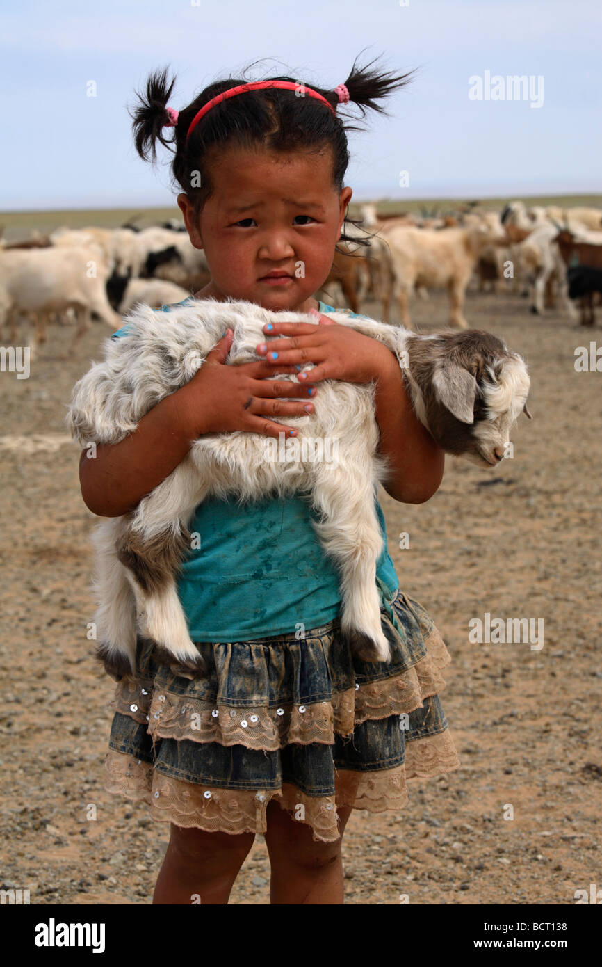 Portrait of mongolian little girl holding a lamb in her arms, Mongolia ...