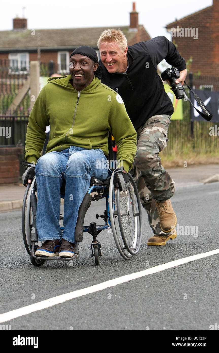 Former athlete Linford Christie is helped along in a wheelchair during a Street Athletics event. Stock Photo