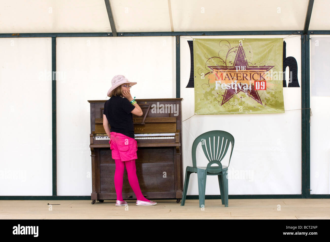 Young girl in pink, black and cowboy hat on a deserted stage at the Maverick alternative country music festival Stock Photo