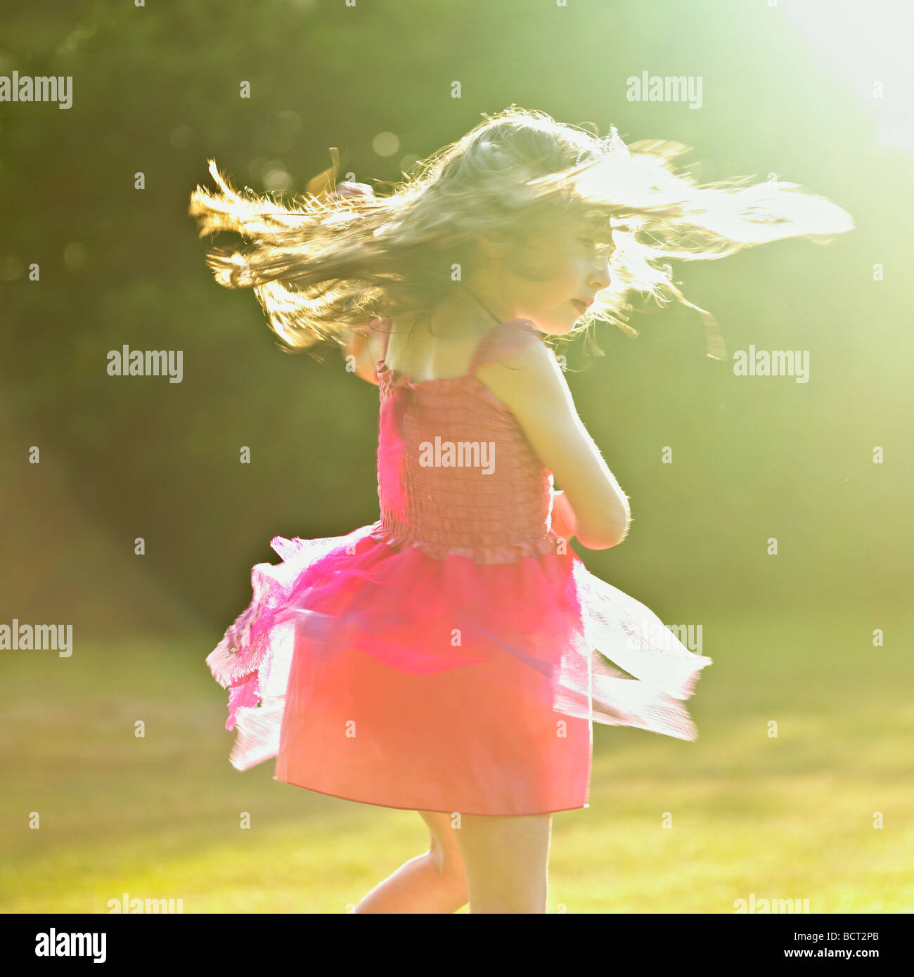 Young girl in a pink dress dancing in the garden summer sun Stock Photo ...