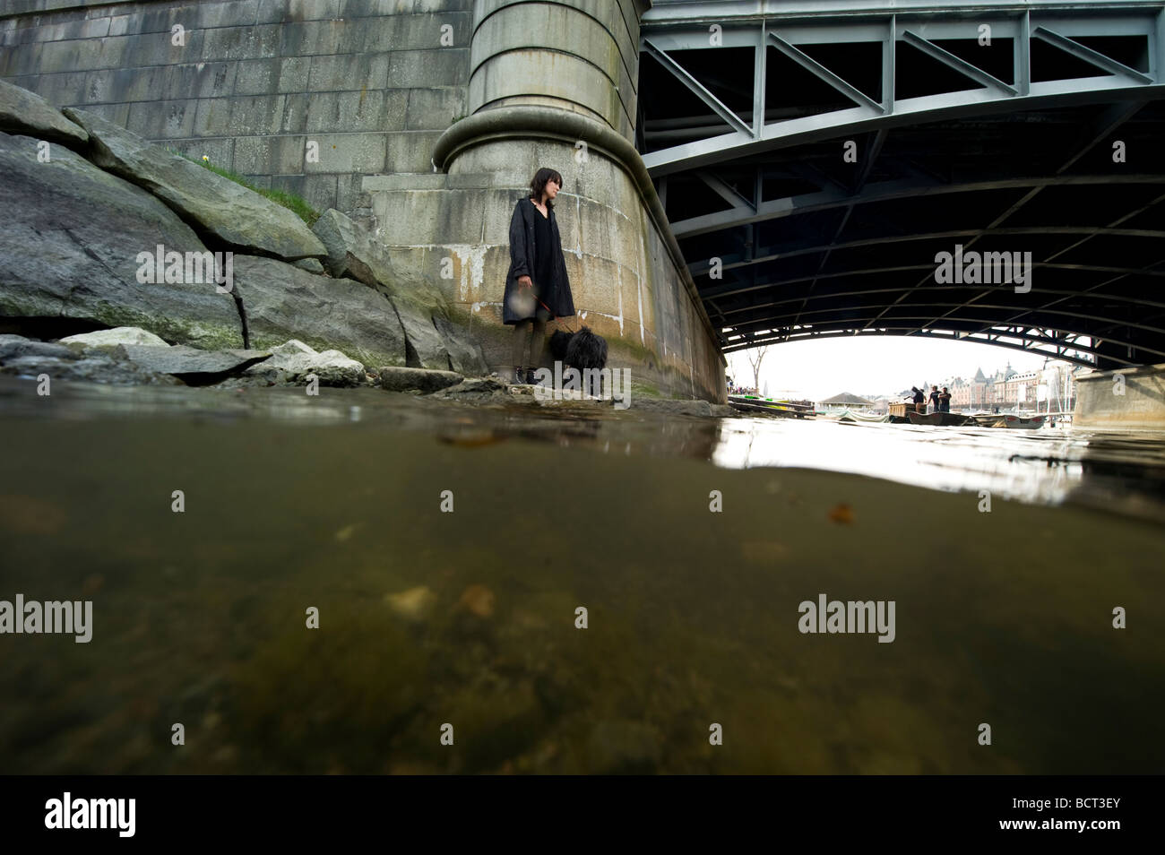 Lonesome girl with black dog standing by a bridge Stock Photo