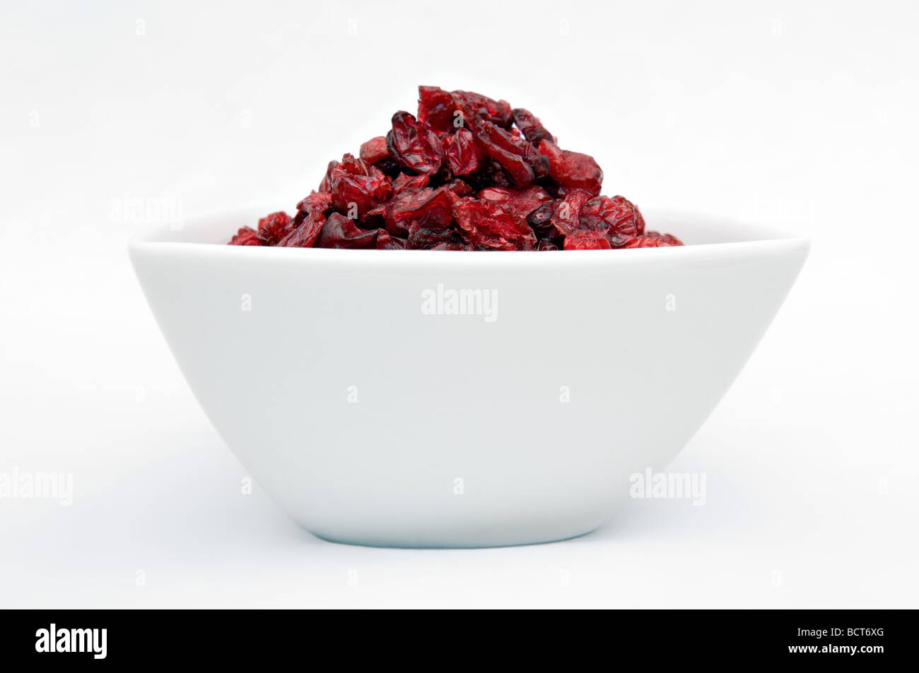 Dried cranberries in white bowl against a white background Stock Photo