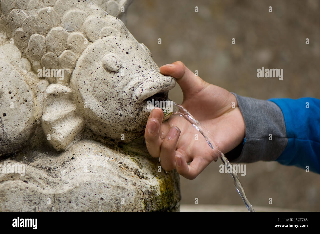 Boys hand feeling the cool spring fresh water from a drinking fountain. Stock Photo