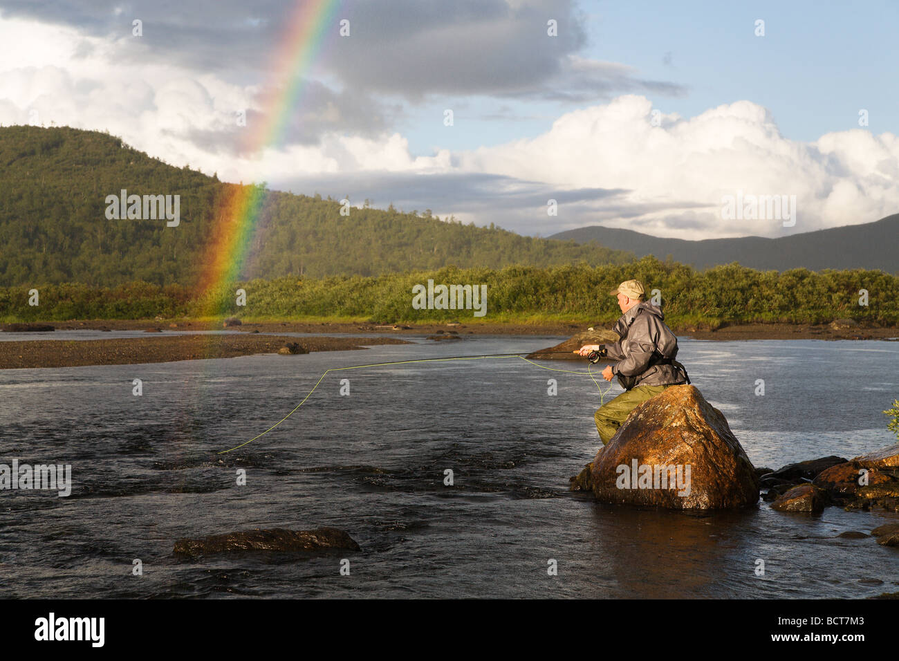 Flyfisherman and rainbow over a troutstream Stock Photo