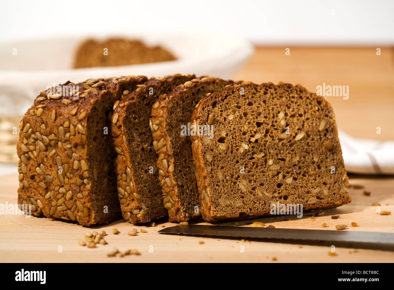 whole grain brown bread, half loaf and three slices, bread knife on cutting plank Stock Photo
