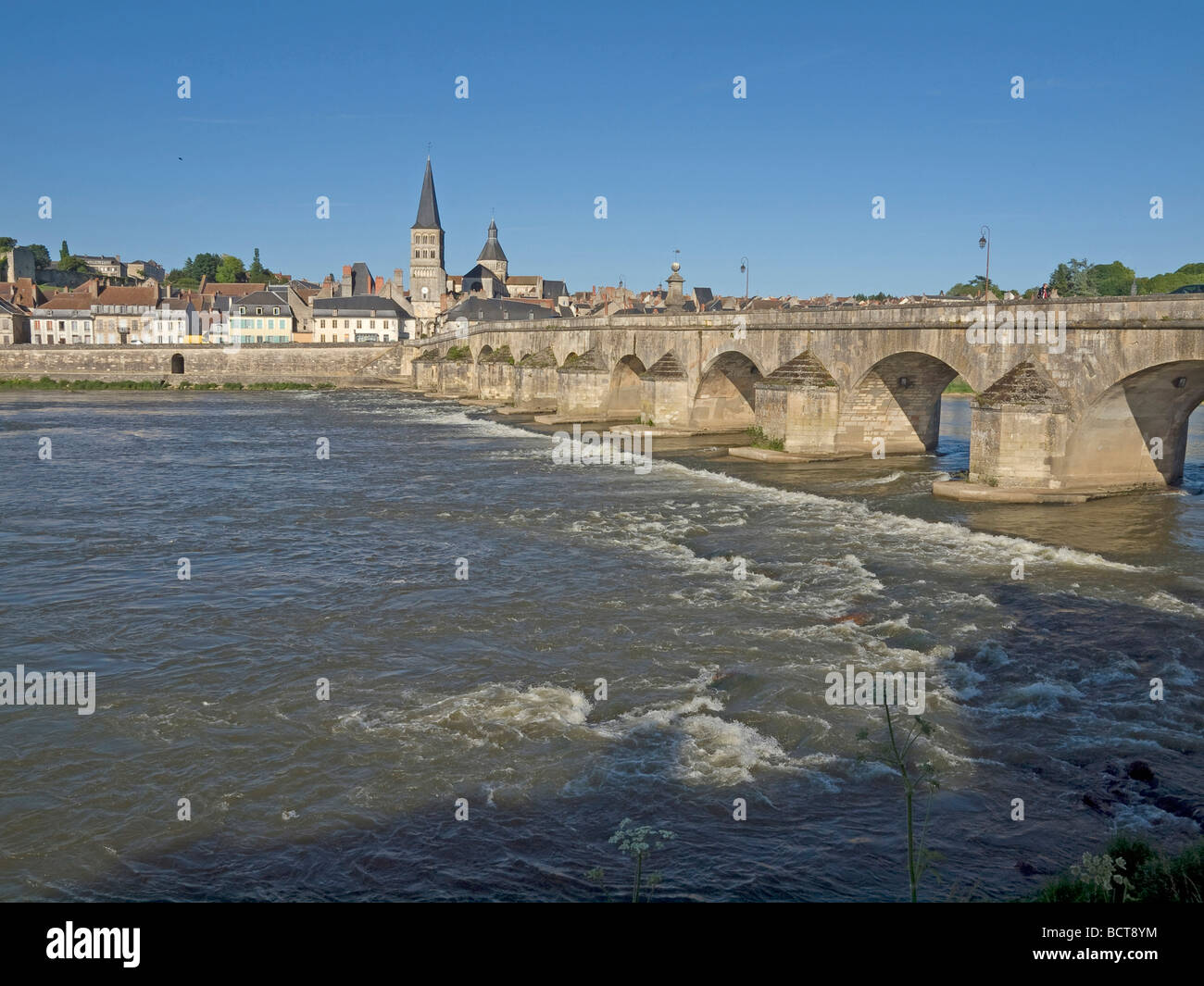 bridge over the river Loire with waves in background the town La Charite sur Loire Stock Photo