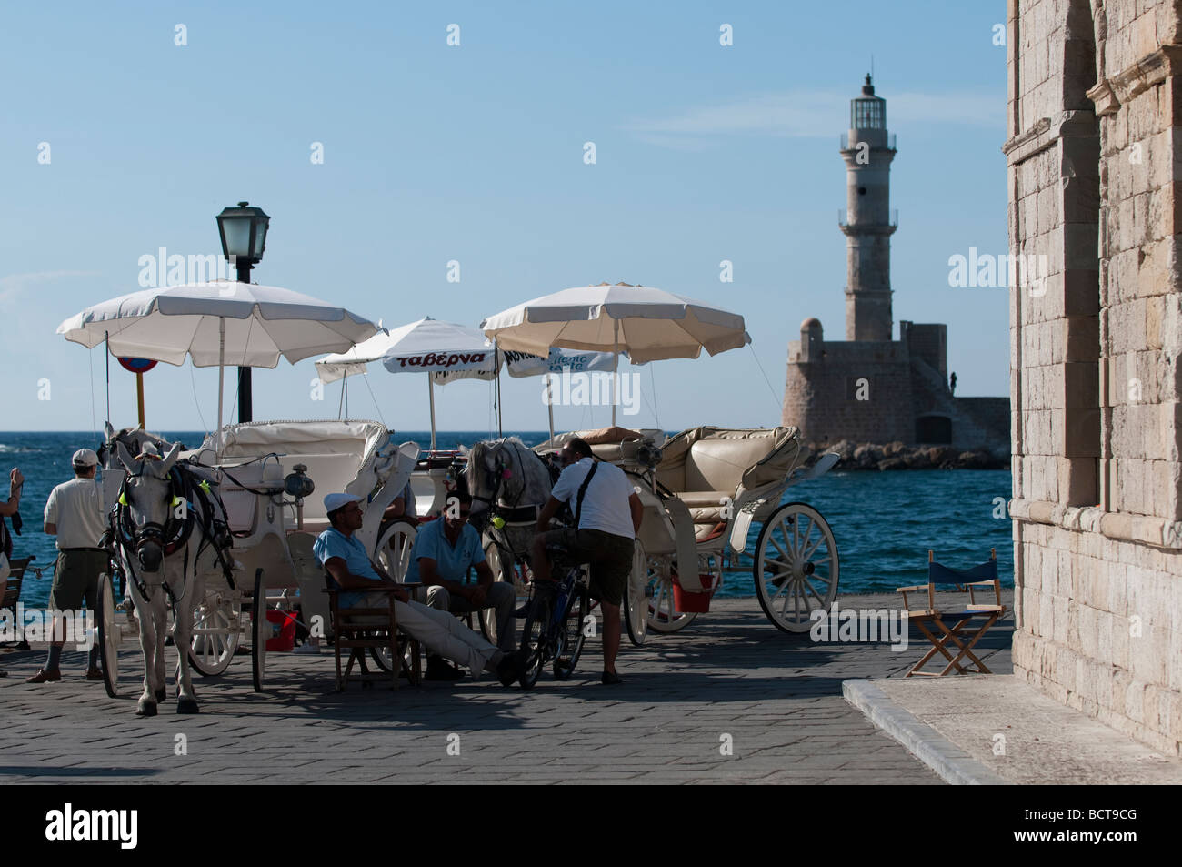 Horsedrawn carriage drivers relaxing in front of the lighthouse and the Venetian Harbour Chania Crete Greece. Stock Photo