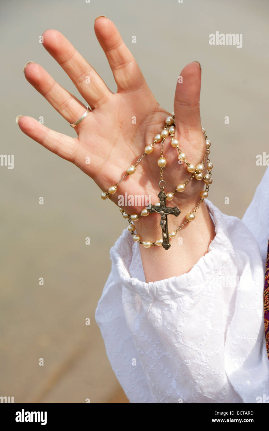 woman holding rosary by lake in her hand Stock Photo