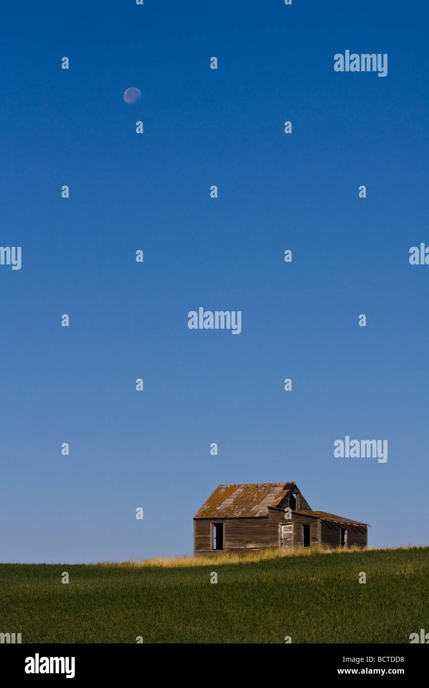 A lone building sits on a small hill on the prairie.  The small homestead has been long forgotten and is falling apart. Stock Photo
