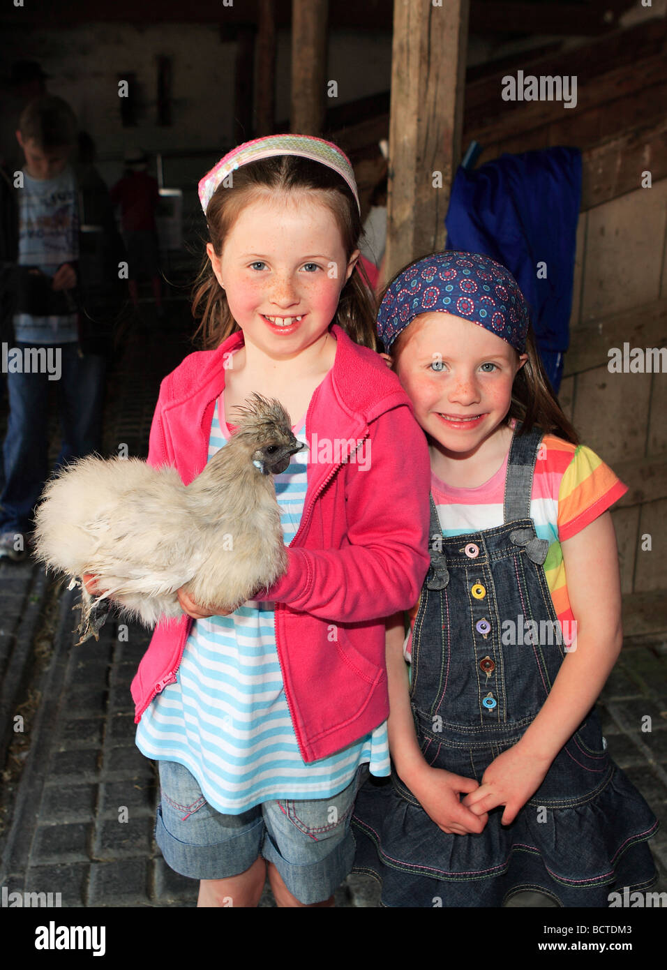 2 sisters smiling with pet chicken Stock Photo Alamy