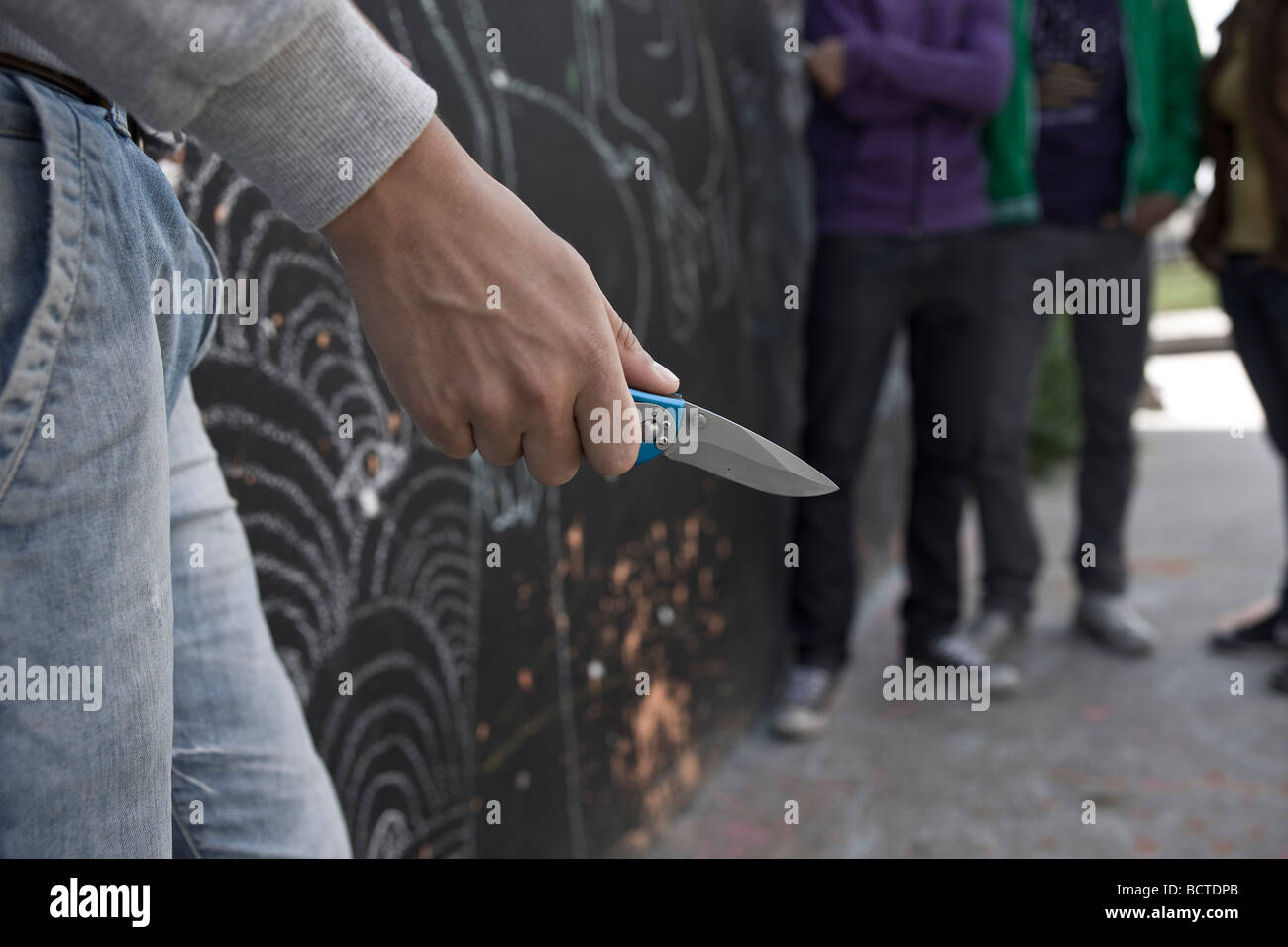 Adolescent threatening a group with a knife Stock Photo
