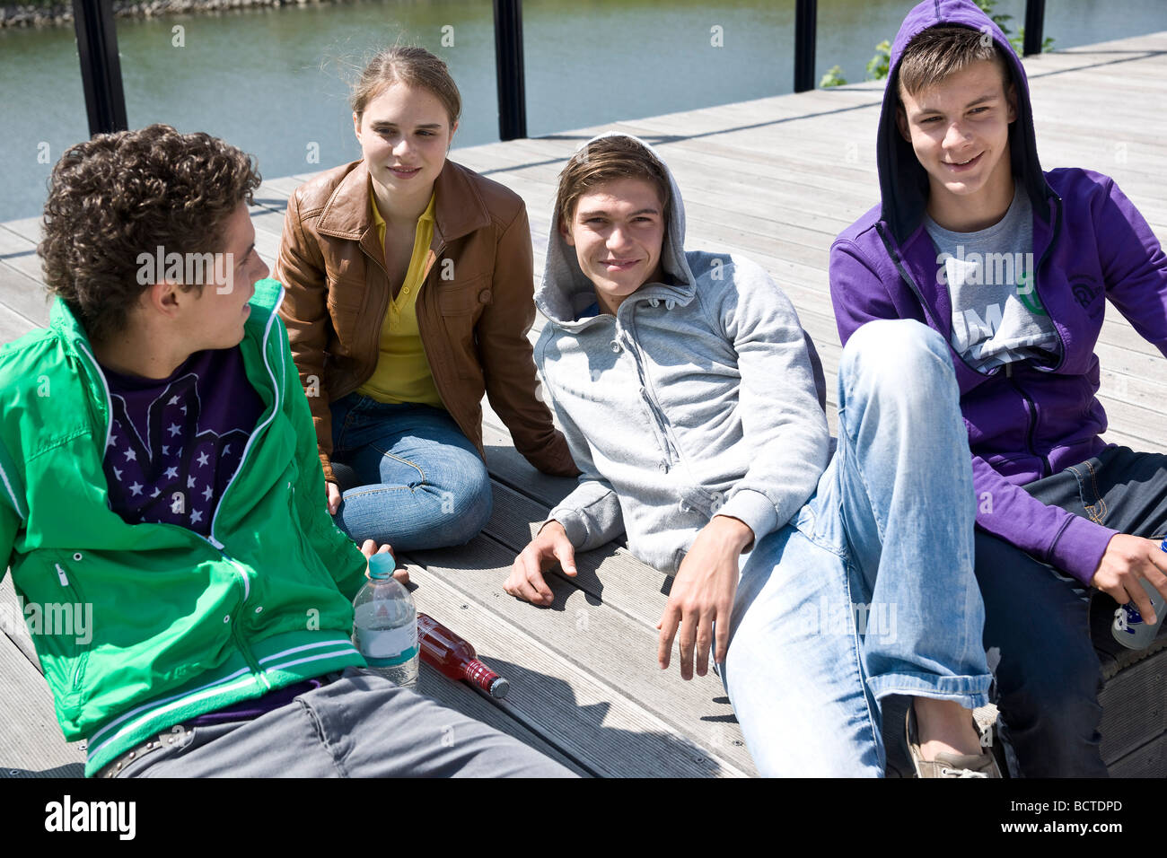 Three boys and a girl sitting on the floor, relaxing in the sun Stock ...