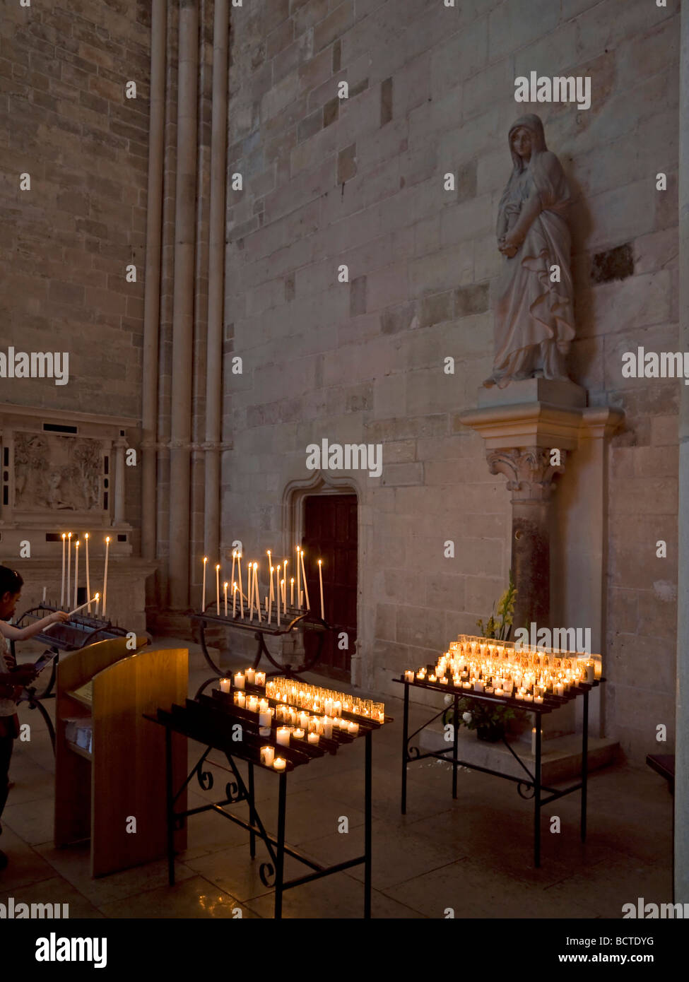 interior view in the church Sainte Marie Madeleine with candles on tables at metal above a sculpture with a sad woman in Vezelay Stock Photo