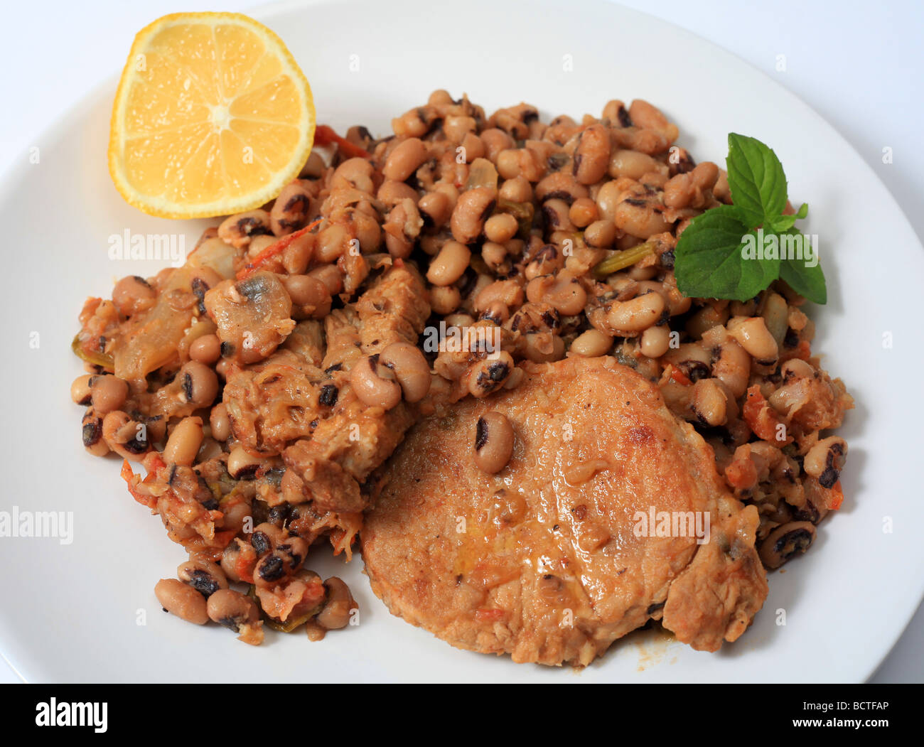 A meal of pork cooked with black eyed beans tomato celery onions and olive oil a traditional Greek recipe Stock Photo