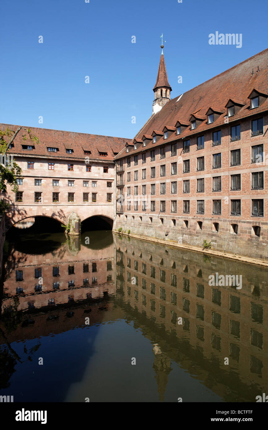 Public historic Heilig-Geist-Spital Holy Spirit hospital, retirement home, church tower, courtyard, arcades, reflection, old to Stock Photo