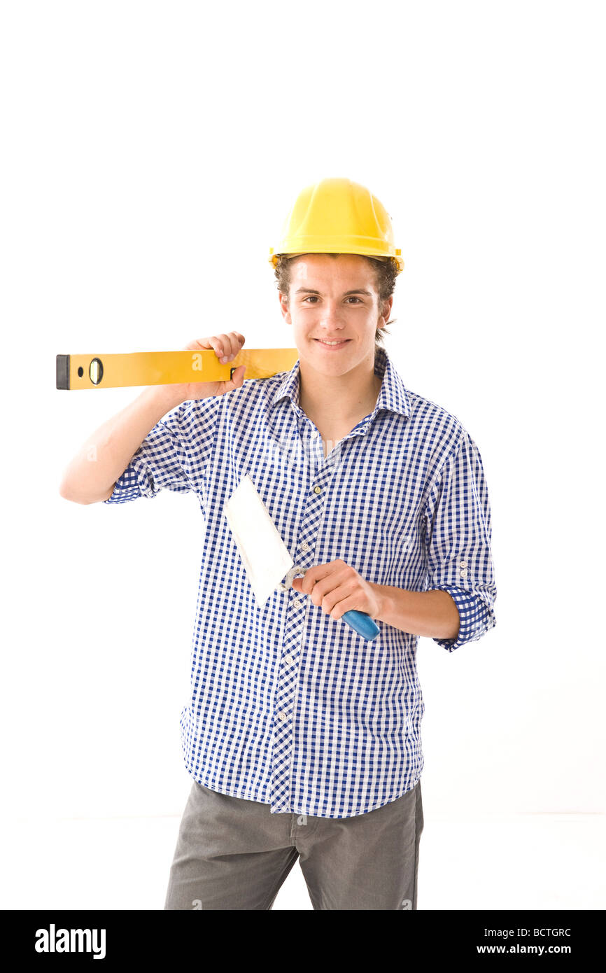 Trainee wearing a hard hat, with a water level and a trowel Stock Photo