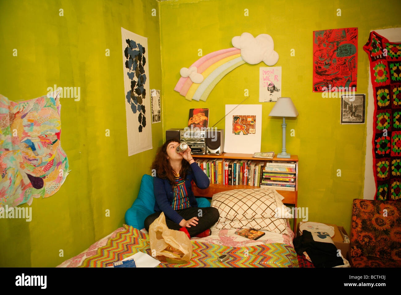 Surrounded by art a college aged punk rocker drinks beer on her bedroom ...