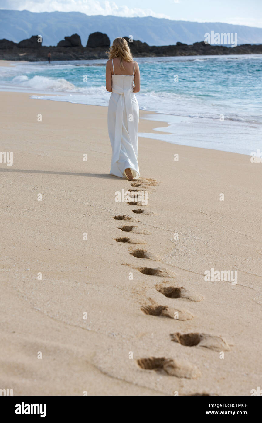 A woman walks along the beach leaving footprints in the sand Stock ...