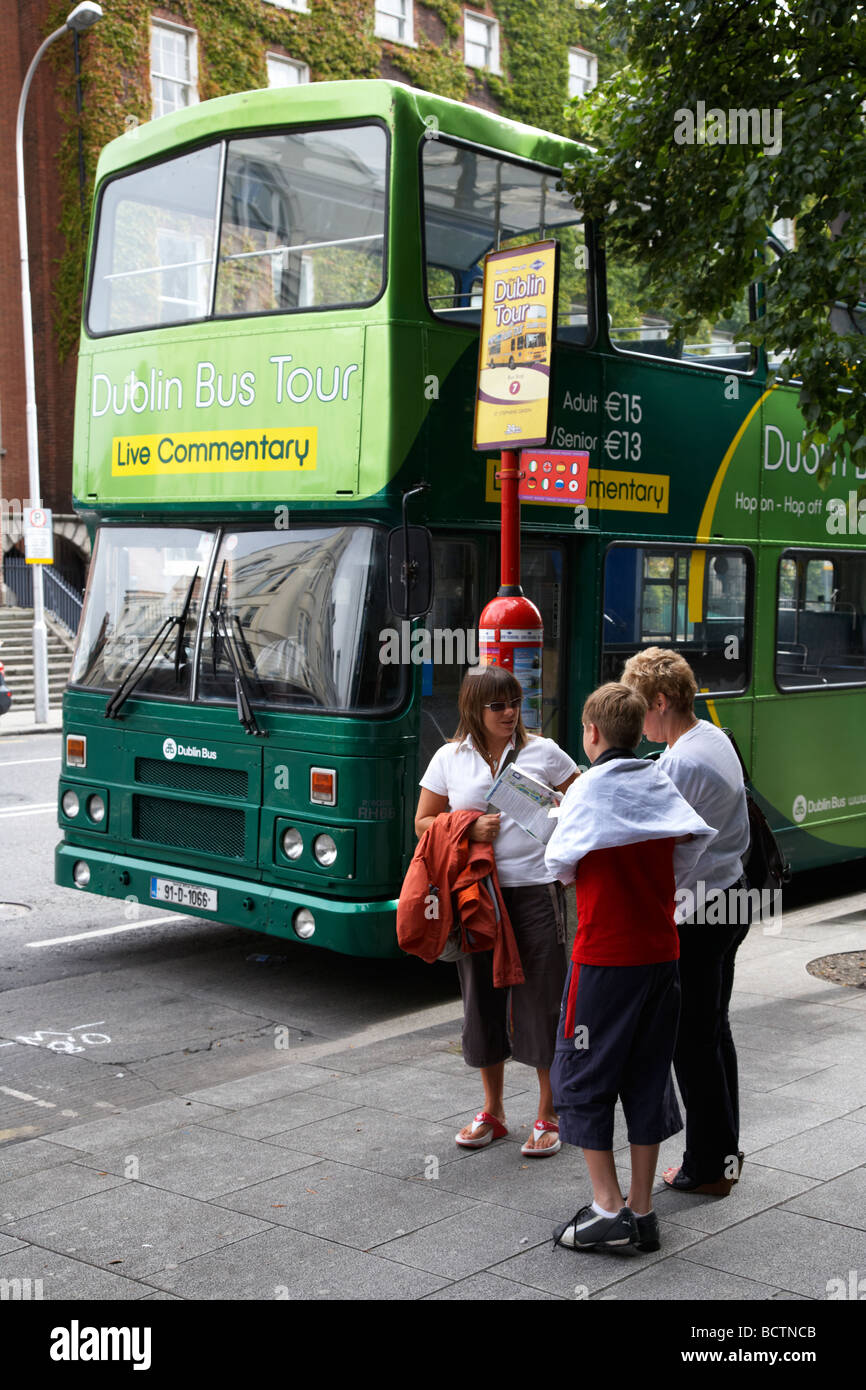 tourists with map stand in front of dublin bus tour bus at stop dublin city centre republic of ireland Stock Photo