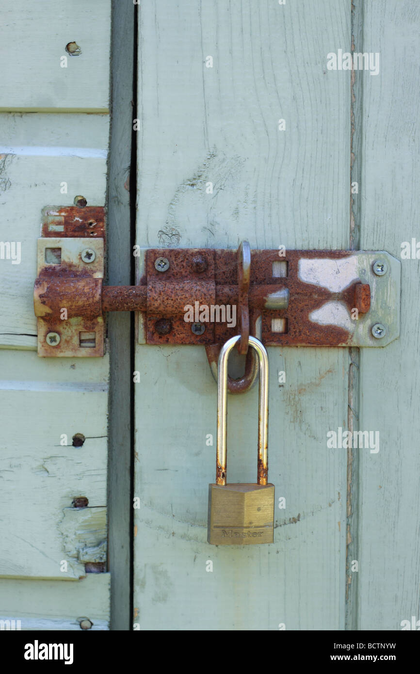 Sliding bolt on a blue wooden shed, secured with a Minster padlock. Stock Photo