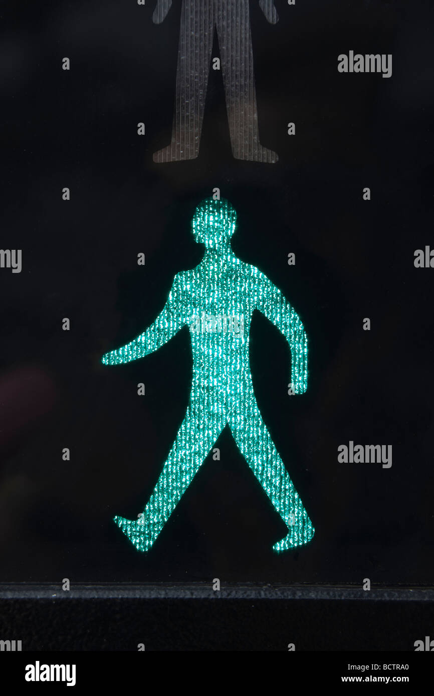 Close up of illuminated walking green man safe to cross road symbol on a pedestrian crossing traffic lights. England UK Britain Stock Photo