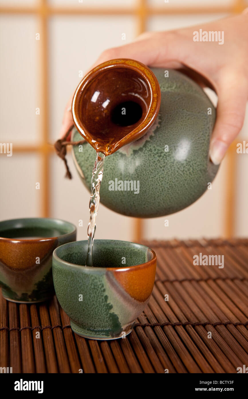 Hand pouring japanese sake in traditional cups Stock Photo Alamy