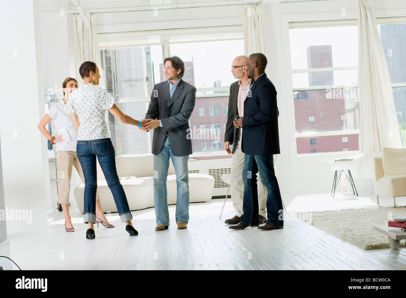 Woman shaking hands with a man with their three friends standing beside them Stock Photo