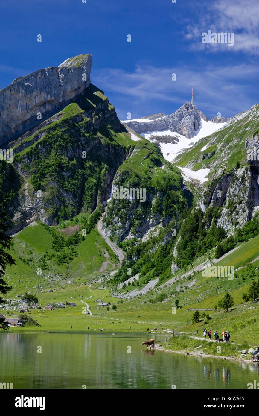 Hikers going along the Seealpsee lake shoreline, Säntis in background Stock Photo