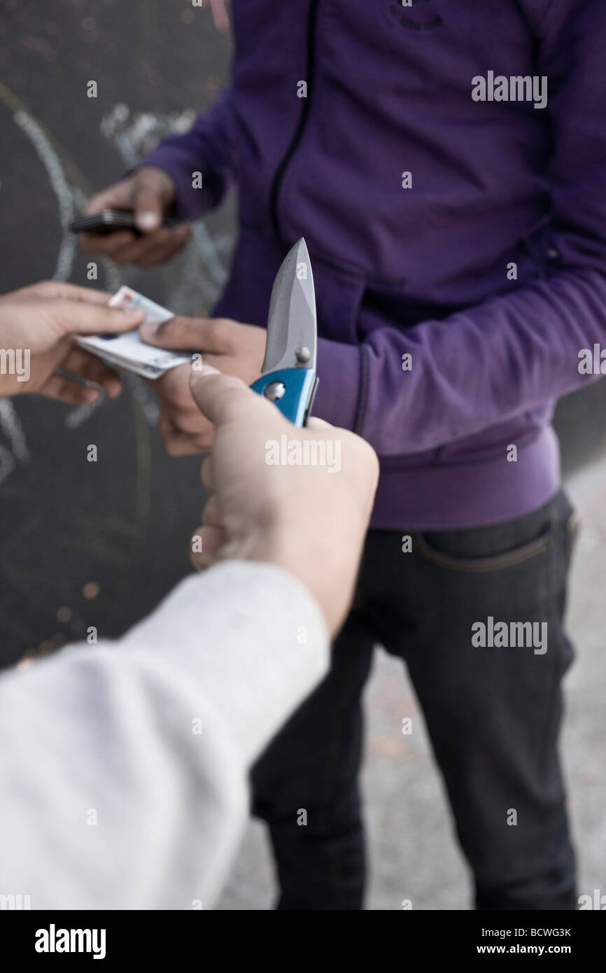 Boy threatening with a knife, wanting money and mobile phone Stock Photo