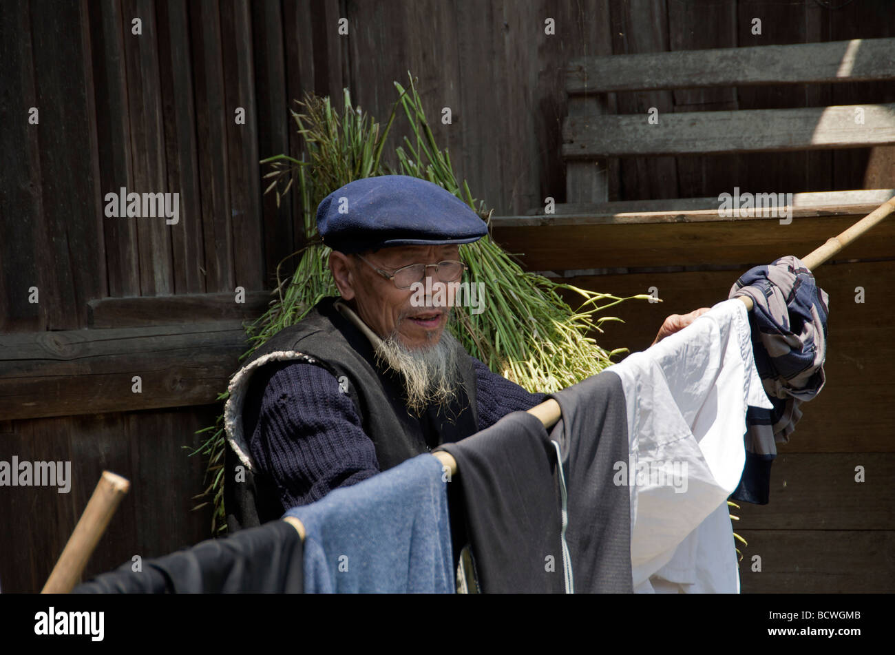 Old Dong man hanging out washing Maan near Sanjiang Guangxi China Stock Photo