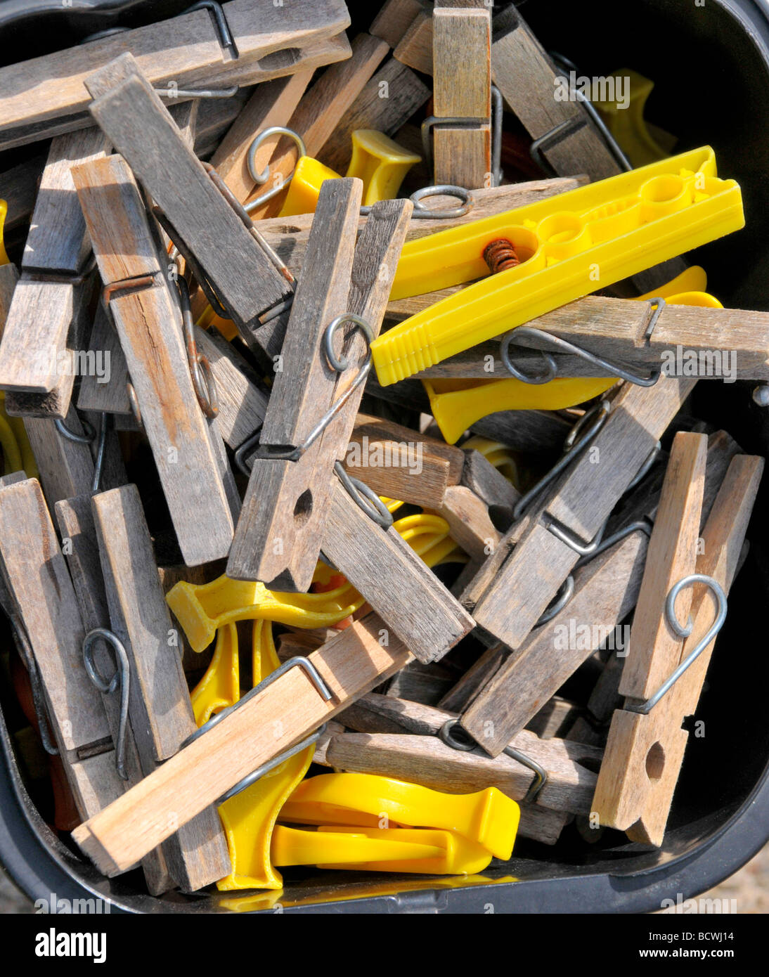 A plastic tub of wooden and plastic clothes pegs. Stock Photo