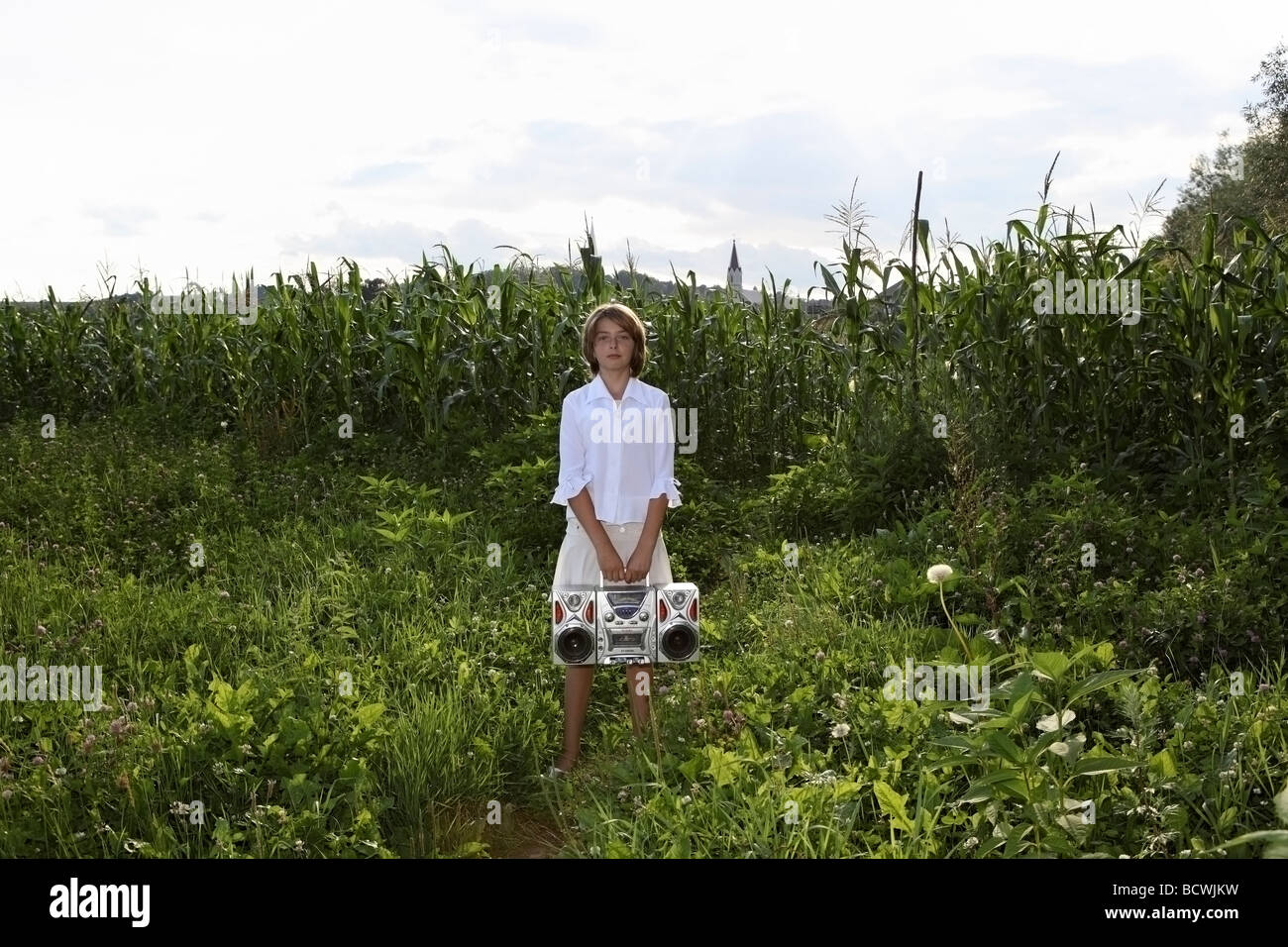 Young girl with 80's portable stereo in front of a maize field in Transylvania. Stock Photo