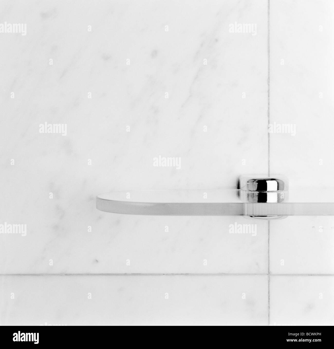 A glass bathroom shelf on a marble wall with chrome fittings Stock