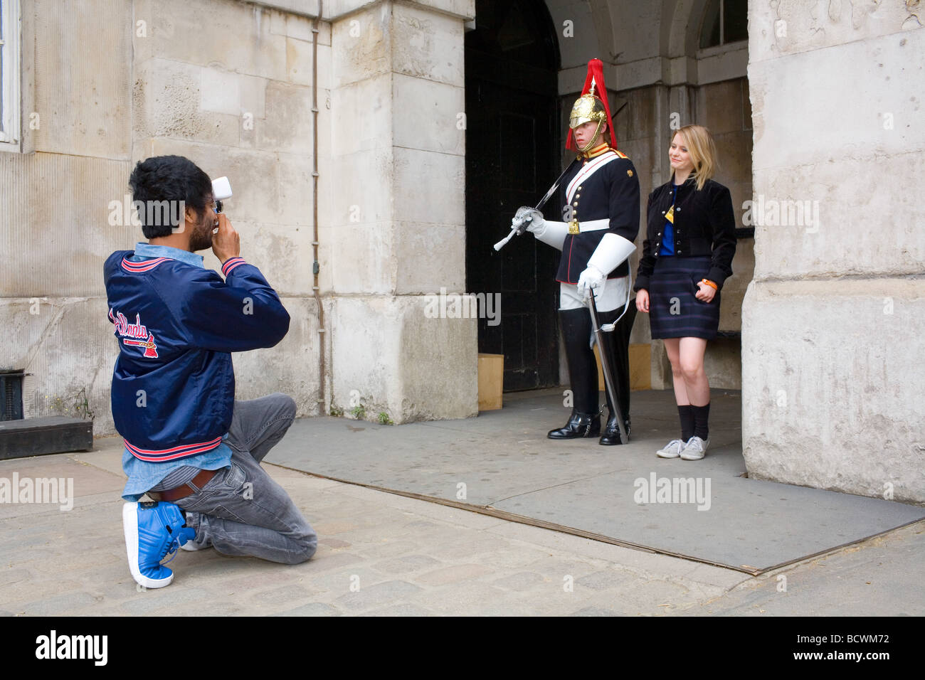 A young Asian man takes a photograph of a petite pretty blonde girl posing with a trooper at Horse Guards Parade in Whitehall Stock Photo