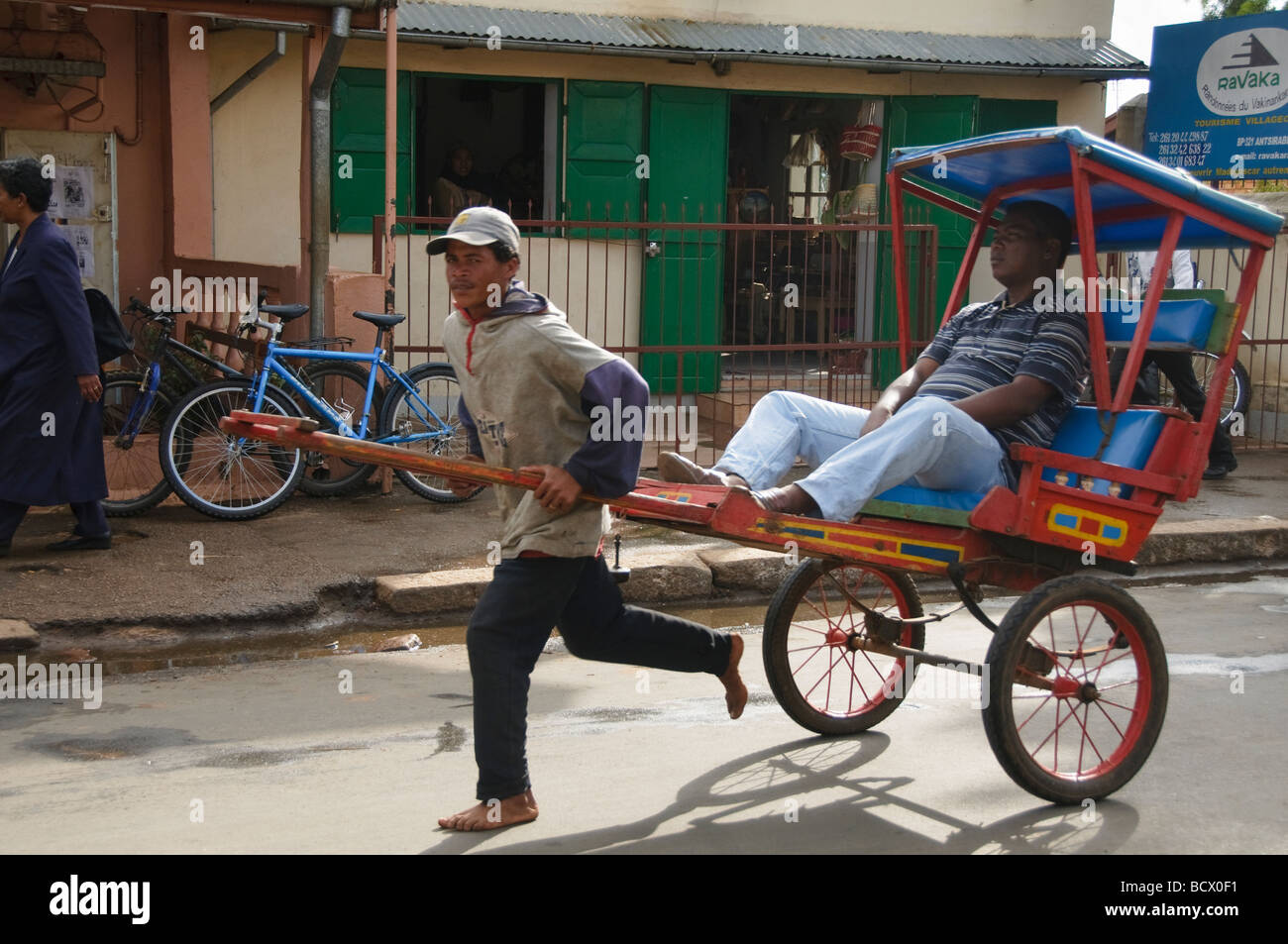 Pousse Posuse pousse pousse driver on the run in Antisirabe Madagascar Stock Photo ...