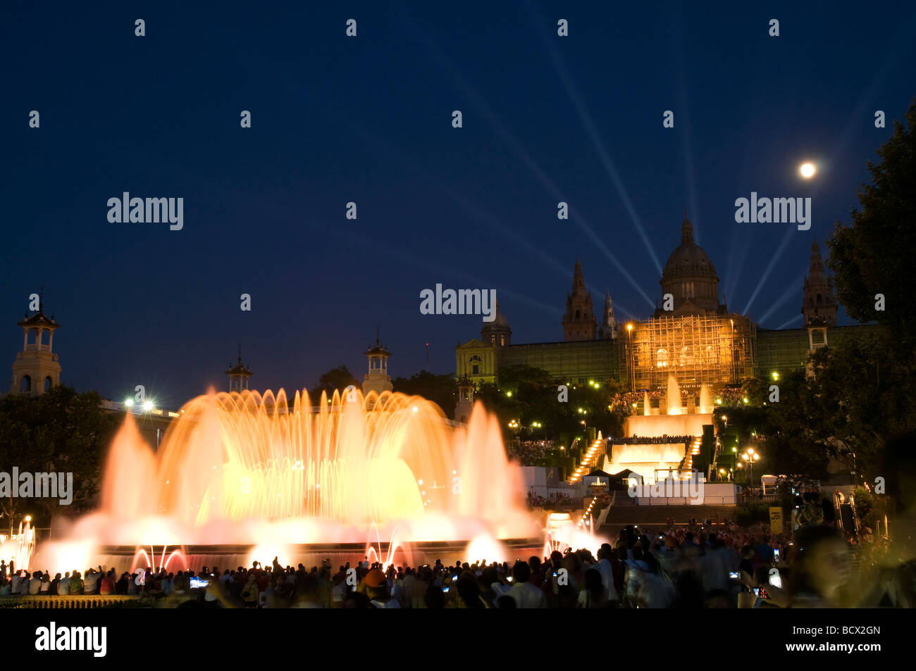 illuminated magic Singing Fountain Font Màgica at night with moon and Palace nationale in the background, Barcelona, Spain Stock Photo