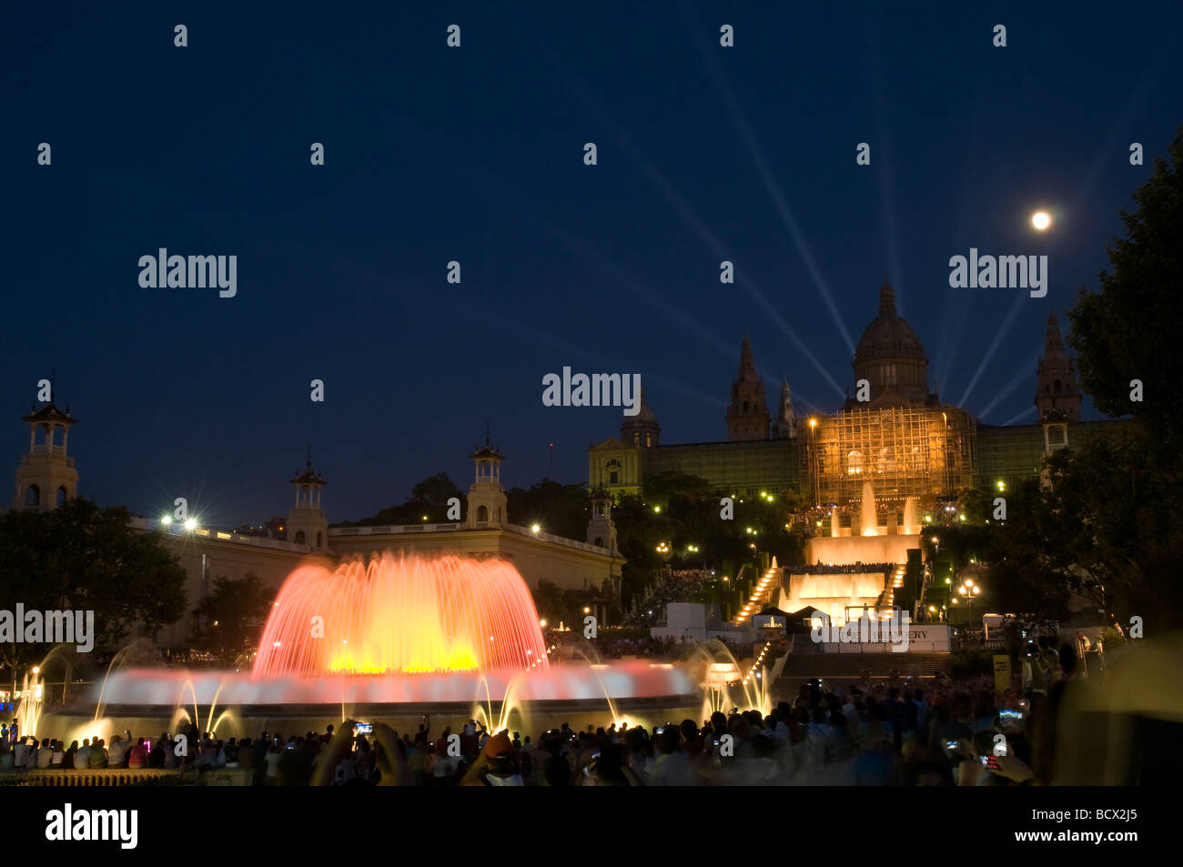 illuminated magic Singing Fountain Font Màgica at night with moon and Palace nationale in the background, Barcelona, Spain Stock Photo