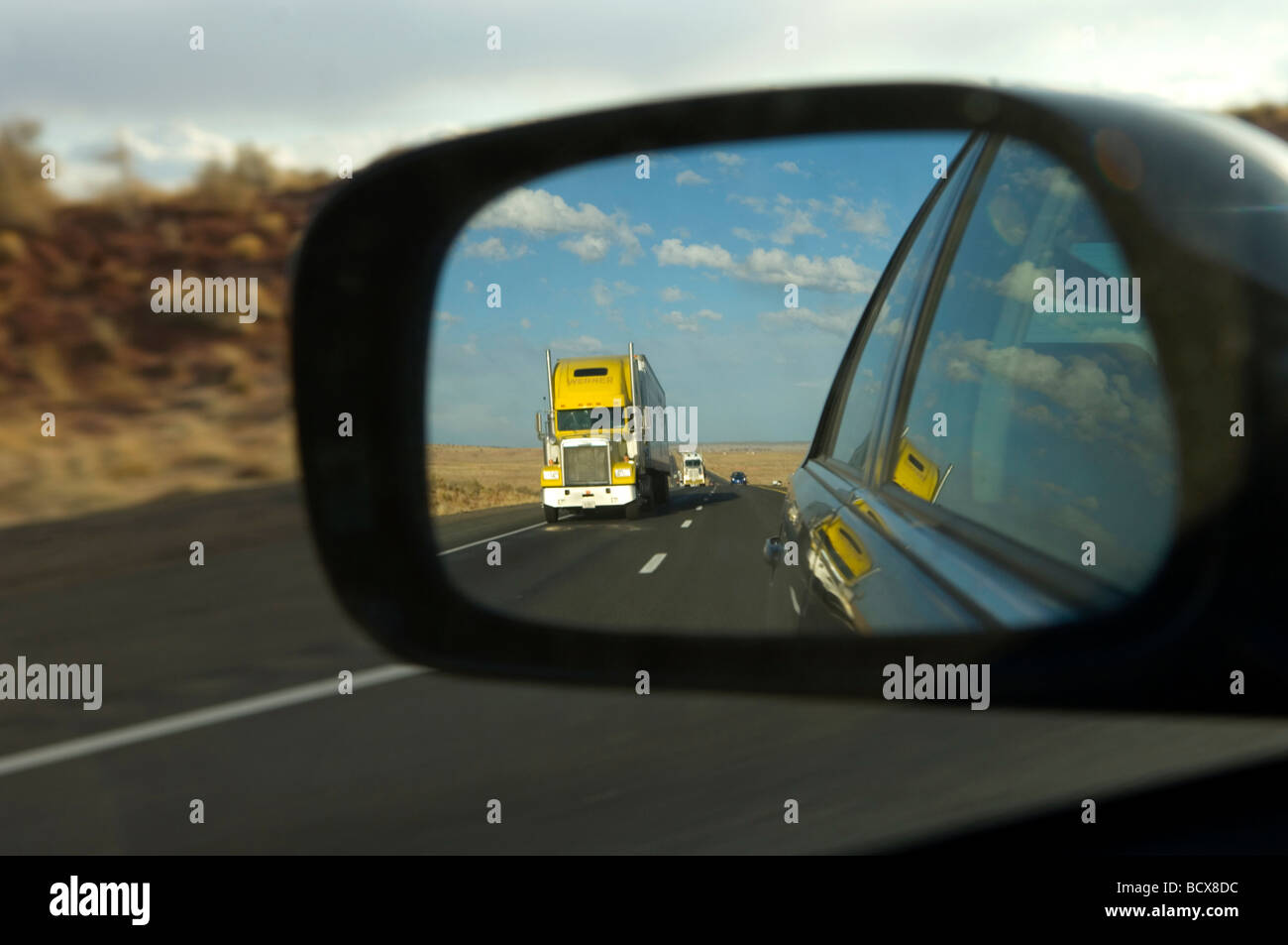 Truck in Rear View Mirror of car on highway. Stock Photo