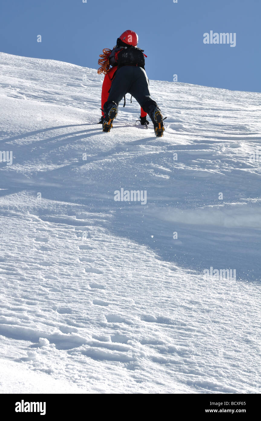 young man climbing the frozen snowy summit of a mountain in the Italian alps Stock Photo